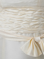 longue robe bustier beige en taffetas de soie naturelle, vaguelettes à la taille et noeud détachable, jupe évasée, robe gala